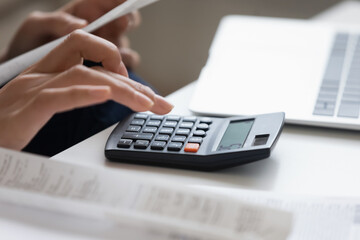 Crop close up of woman calculate expenses expenditures on calculator machine managing family budget...