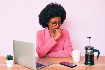 Young african american woman working at desk using computer laptop feeling unwell and coughing as symptom for cold or bronchitis. health care concept. - obrazy, fototapety, plakaty