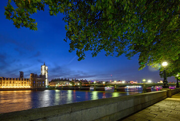 Fototapeta na wymiar Houses of Parliament in Westminster, London, UK. The Houses of Parliament are by the River Thames with view of Westminster Bridge. Vehicle light trails and trees above with long exposure motion blur.