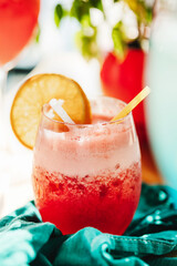 red fruit cocktail in a glass with a straw on a blue napkin