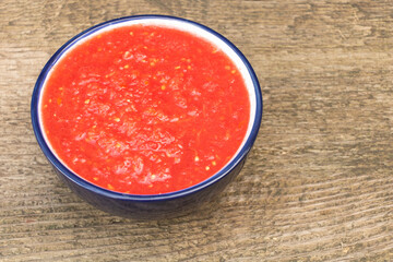 Raw tomato juice on a plate, wooden background