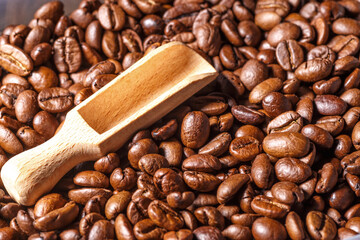 Freshly roasted coffee beans background.Dark roasted coffee beans with scoop on wooden background.