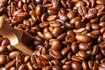 Freshly roasted coffee beans background.Dark roasted coffee beans with scoop on wooden background.