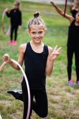 Girl gymnast training with hoop and smiling on sports playground - obrazy, fototapety, plakaty