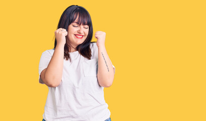 Young plus size woman wearing casual clothes excited for success with arms raised and eyes closed celebrating victory smiling. winner concept.