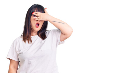 Young plus size woman wearing casual clothes peeking in shock covering face and eyes with hand, looking through fingers with embarrassed expression.