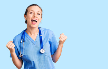 Young beautiful blonde woman wearing doctor uniform and stethoscope celebrating surprised and...