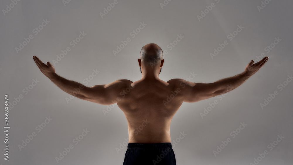 Wall mural perfect shape. rear view of muscular strong man with naked torso standing with outstretched arms iso - Wall murals