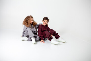 curly long-haired girl and boy in tracksuits on a white background