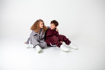 curly long-haired girl and boy in tracksuits on a white background