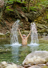 Man with beard enjoys swimming in mountain river