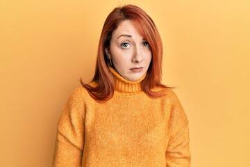 Beautiful redhead woman wearing casual winter sweater over yellow background skeptic and nervous, frowning upset because of problem. negative person.