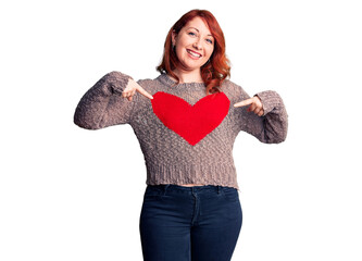 Young beautiful redhead woman wearing casual heart sweater looking confident with smile on face, pointing oneself with fingers proud and happy.