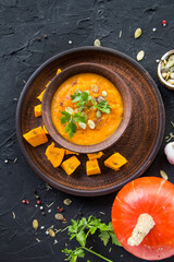 Delicious healthy pumpkin soup, herbs, and ingredients for the dish. Creative atmospheric decoration