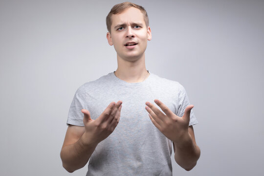 Studio Portrait Concept Of A Smiling Young Man Talking On A White Background. He Stands Directly In Front Of The Camera In Different Poses With Different Emotions.