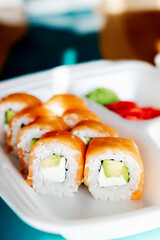 fish and avocado rolls in a white shipping container