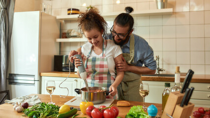 Young couple preparing a meal together in the kitchen. Italian man, chef cook helping his...