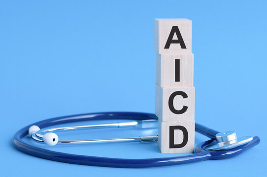 AICD word written on wooden blocks and stethoscope on light blue background