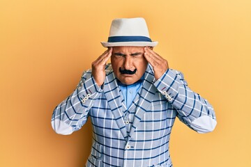 Mature middle east man with mustache wearing vintage and elegant fashion style with hand on head for pain in head because stress. suffering migraine.
