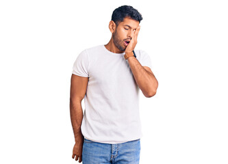 Young latin man wearing casual clothes yawning tired covering half face, eye and mouth with hand. face hurts in pain.