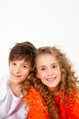 curly haired girl in an orange long sleeve t-shirt sits next to her friend in a white t-shirt