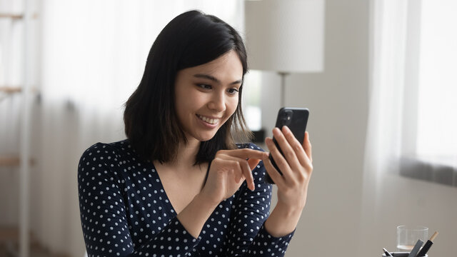 Smiling young Vietnamese woman look at cellphone screen talk speak on video call on gadget. Happy asian girl client customer browse wireless internet on modern smartphone device. Technology concept.