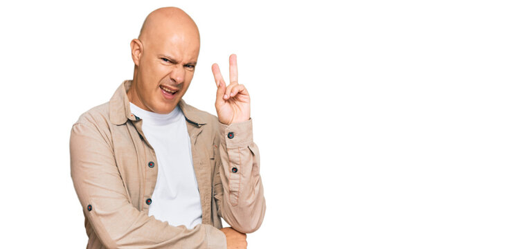 Middle age bald man wearing casual clothes smiling with happy face winking at the camera doing victory sign. number two.