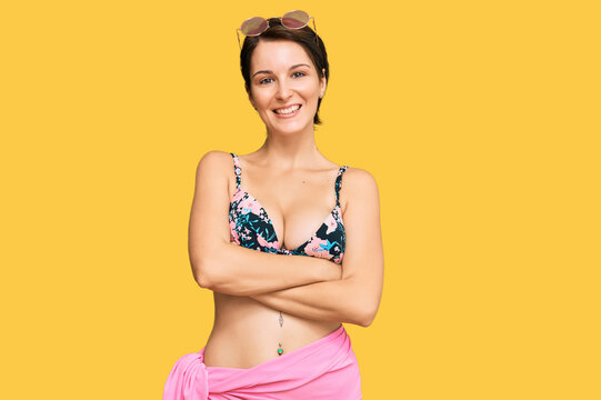 Young brunette woman with short hair wearing bikini happy face smiling with crossed arms looking at the camera. positive person.