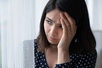Fototapeta premium Depressed young asian woman look in window distance mourning yearning at home. Upset unhappy Vietnamese female loner outcast feel distressed anxious, lack communication. Depression concept.