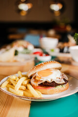 Hamburger with meat Patty and chicken egg on a plate with French fries