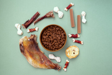 Dog delicacy food and feed in bowl on green background. Variety of dog treats.