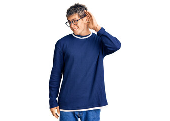 Fototapeta premium Young handsome man wearing casual clothes and glasses smiling with hand over ear listening an hearing to rumor or gossip. deafness concept.