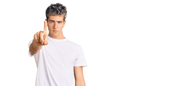 Young handsome man wearing casual white tshirt pointing with finger up and angry expression, showing no gesture