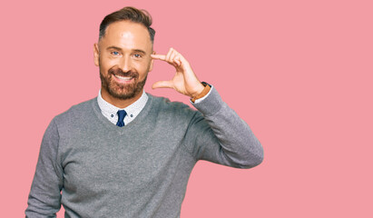 Handsome middle age man wearing business clothes smiling and confident gesturing with hand doing small size sign with fingers looking and the camera. measure concept.