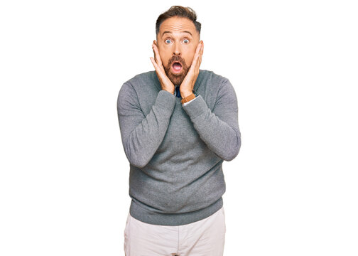 Handsome middle age man wearing business clothes afraid and shocked, surprise and amazed expression with hands on face