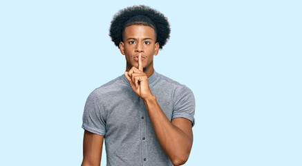 Fototapeta na wymiar African american man with afro hair wearing casual clothes asking to be quiet with finger on lips. silence and secret concept.