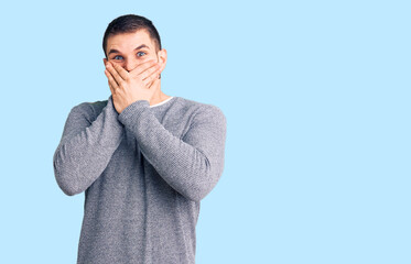 Young handsome man wearing casual sweater shocked covering mouth with hands for mistake. secret...
