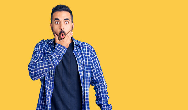 Young hispanic man wearing casual clothes looking fascinated with disbelief, surprise and amazed expression with hands on chin