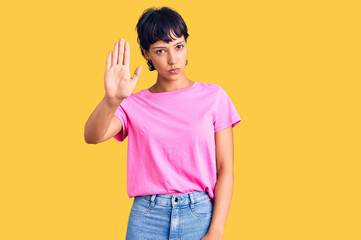 Young brunette woman with short hair wearing casual clothes doing stop sing with palm of the hand. warning expression with negative and serious gesture on the face.