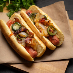 Hot dog with jalapeno pepper, bacon and caramelized onion on dark background