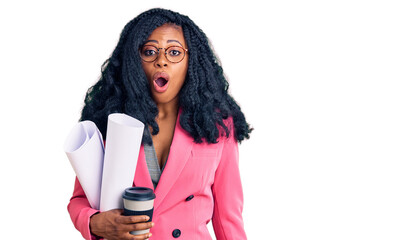 Beautiful african american woman holding paper blueprints and drinking coffee scared and amazed with open mouth for surprise, disbelief face