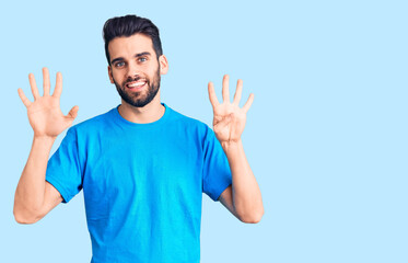 Young handsome man with beard wearing casual t-shirt showing and pointing up with fingers number nine while smiling confident and happy.