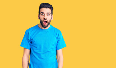 Young handsome man with beard wearing casual t-shirt afraid and shocked with surprise and amazed expression, fear and excited face.