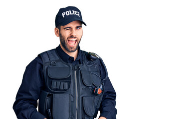 Young handsome man with beard wearing police uniform winking looking at the camera with sexy...