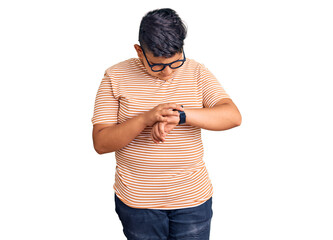 Little boy kid wearing casual clothes and glasses checking the time on wrist watch, relaxed and...