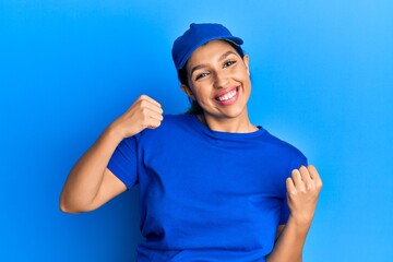 Beautiful brunette woman wearing delivery uniform very happy and excited doing winner gesture with arms raised, smiling and screaming for success. celebration concept.