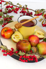 Cozy autumn hot spiced tea with honey, apples and red hawthorn berries on a tray. Still life on white background