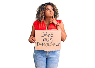 Young african american plus size woman holding save our democracy banner serious face thinking...