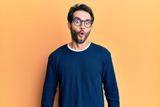 Young hispanic man wearing casual clothes and glasses scared and amazed with open mouth for surprise, disbelief face