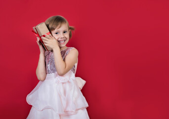 Cute adorable smiling girl holding christmas gift isolated on red